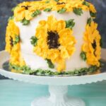 Whole wheat carrot pineapple cake on cake stand with sunflower design buttercream