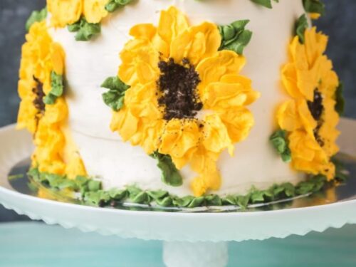 Whole wheat carrot pineapple cake on cake stand with sunflower design buttercream