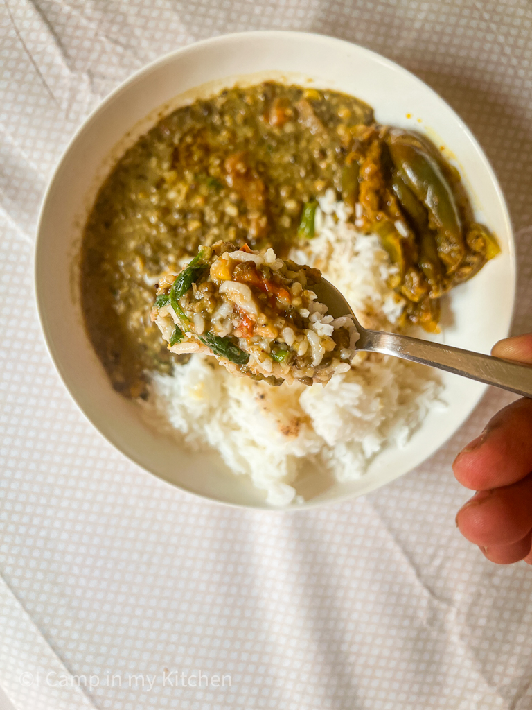 A spoon of delish langar dal with rice and ghee in a bowl